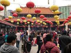 05A People congregate in the courtyard in front of the main hall with red and yellow lanterns Wong Tai Sin temple Hong Kong